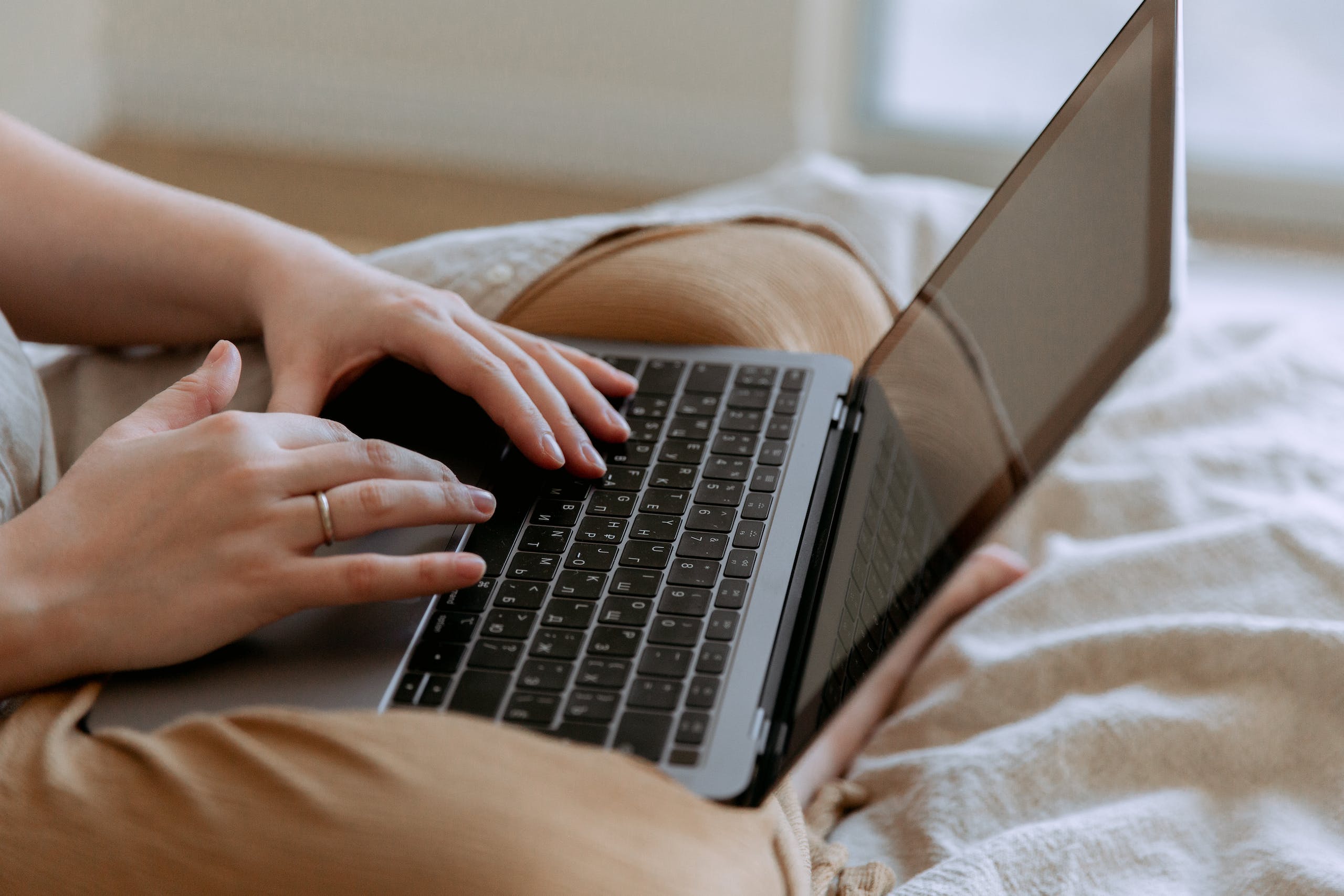 mujer usando portatil en la cama para contactar